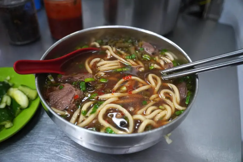 Clear beef noodles after adding hot sauce, mustard greens, and fermented black beans